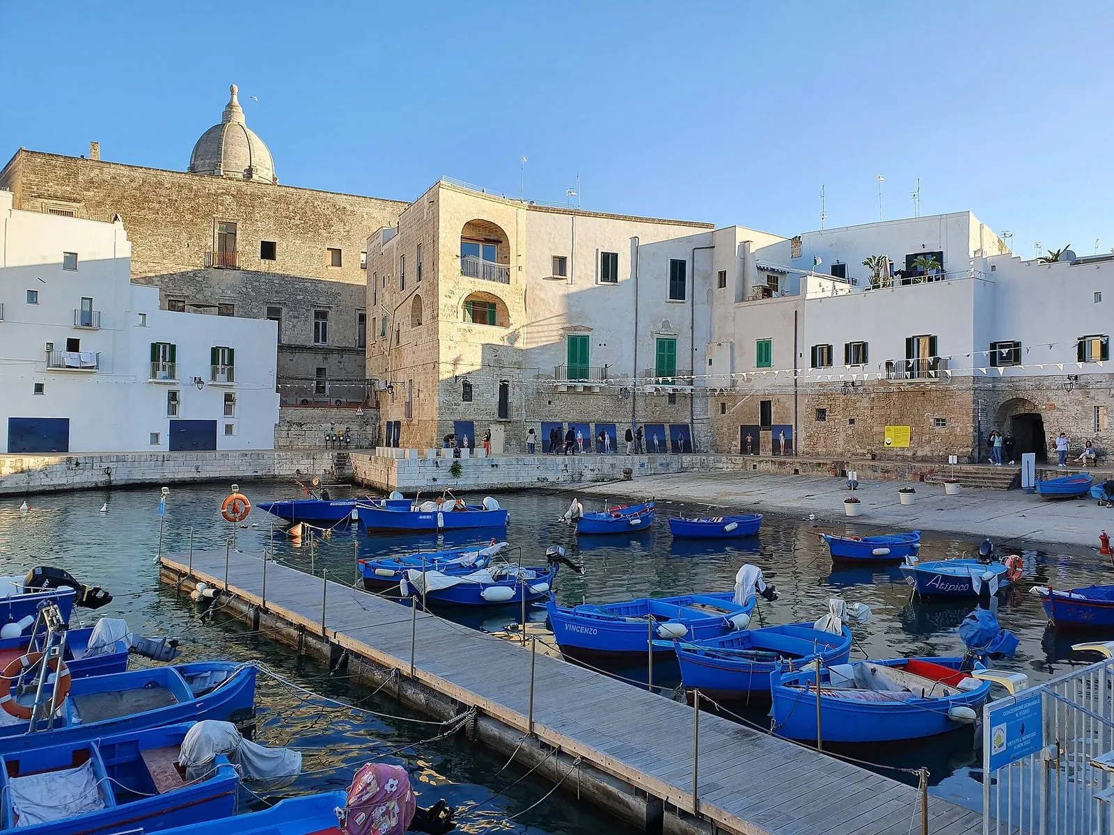 Il porto vecchio di Monopoli con le barche dei pescatori azzurre ormeggiate al pontile e le case bianche e in pietra del centro storico