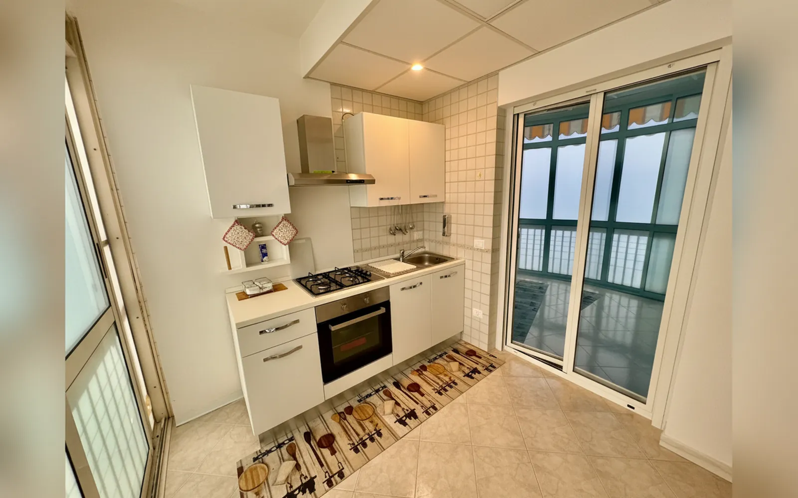 La cucina con il piano cottura e la vetrata verso il balcone